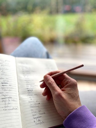 Frauenhand schreibt ein Gedicht in ein Notizbuch